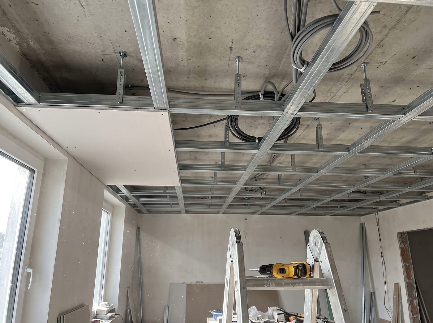 Metallunterkonstruktion einer abgehängten Decke mit Direktabhängern und Leitungen im Hohlraum